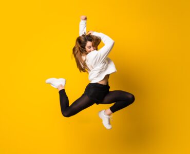 Young Woman Jumping Isolated Yellow Wall Free Image